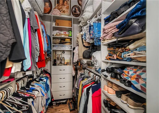 Custom closet system featuring multiple hanging rods, built-in shelving, and drawers
