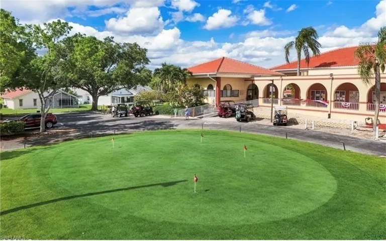 Manicured putting green with multiple flagsticks, bordering a paved cart path