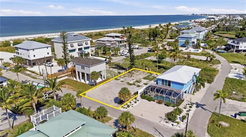 Cleared residential lot situated on a paved road, featuring a level topography and scattered native landscaping