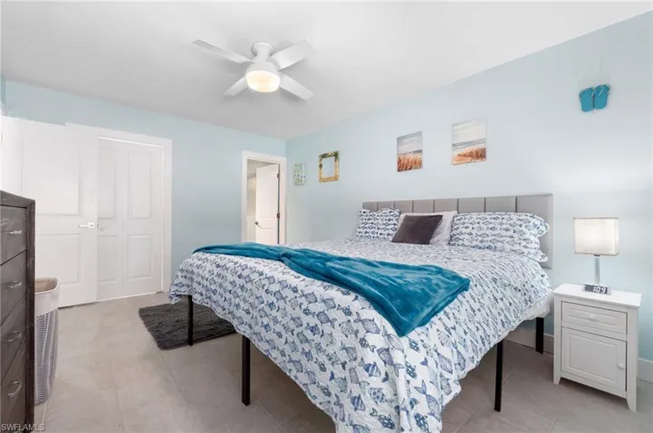 Tiled bedroom with ceiling fan and a closet