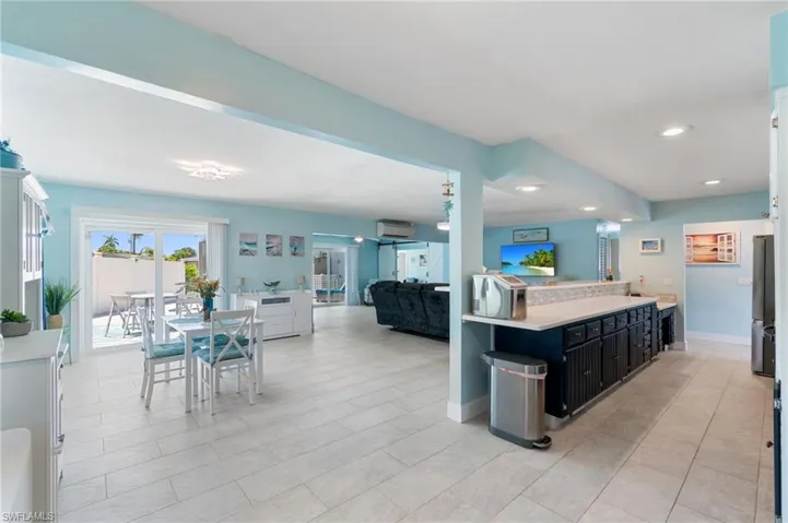 Kitchen featuring a wall unit AC, stainless steel fridge, and light tile floors