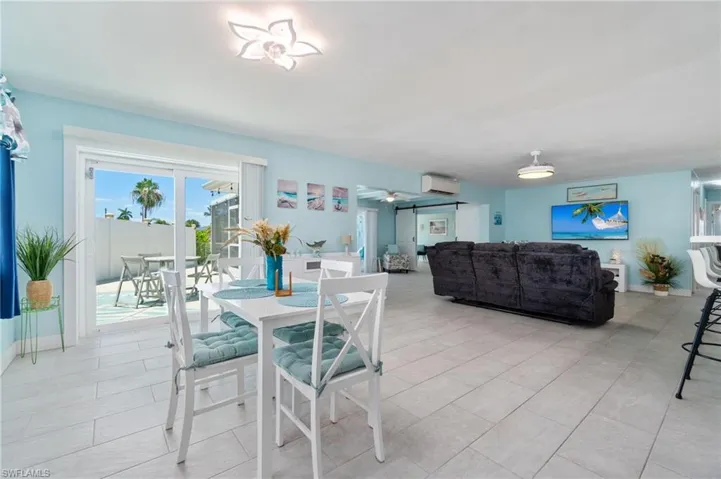 Dining room with a wall mounted AC, ceiling fan, and light tile floors