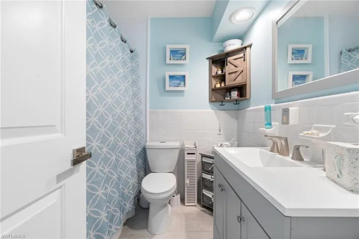 Bathroom featuring tile walls, tasteful backsplash, toilet, tile floors, and large vanity