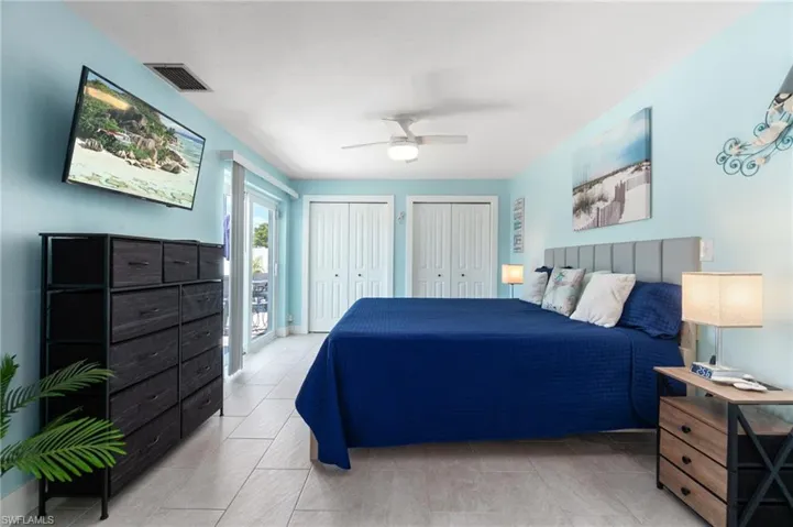 Tiled bedroom with multiple closets and ceiling fan