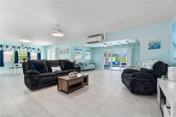 Tiled living room featuring ceiling fan and an AC wall unit