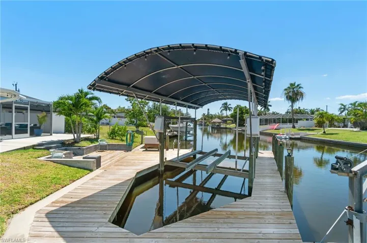 View of dock featuring a yard, glass enclosure, and a water view