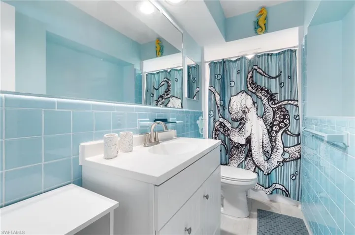 Bathroom featuring oversized vanity, tile walls, and tasteful backsplash