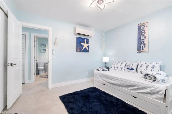 Tiled bedroom with an AC wall unit and connected bathroom