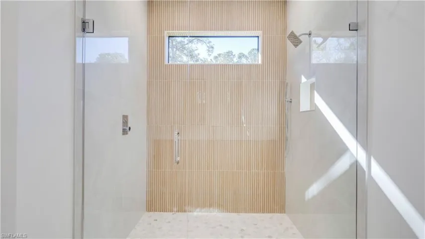 Primary walk-in shower with modern tile and multiple shower heads.