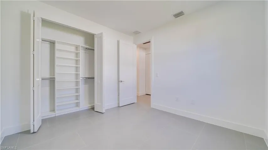 3rd Bedroom closet open showing custom closet system.