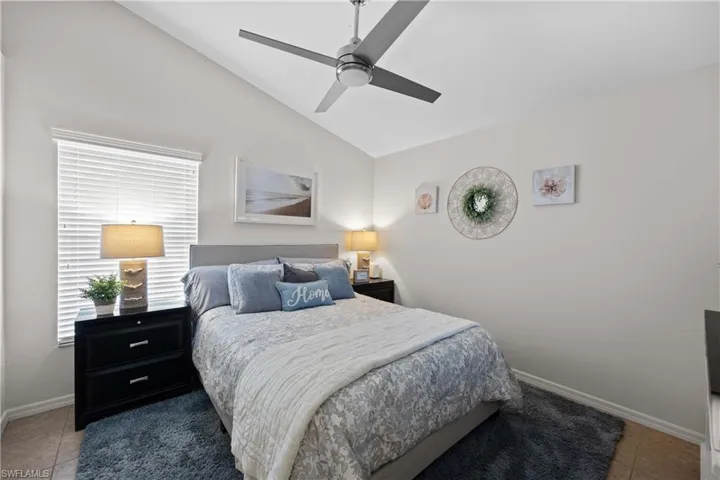 Tiled bedroom featuring ceiling fan and lofted ceiling