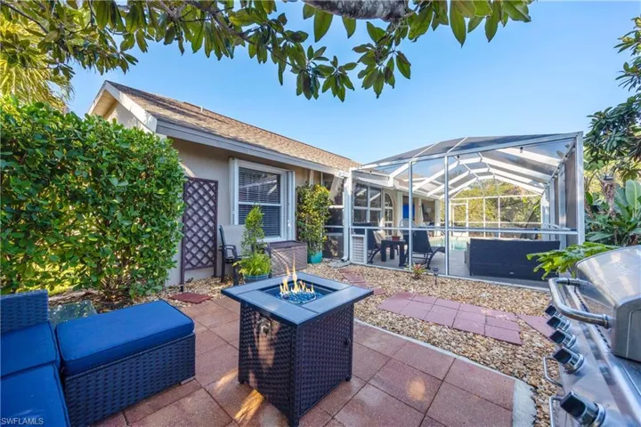 View of patio featuring an outdoor fire pit, a grill, and glass enclosure