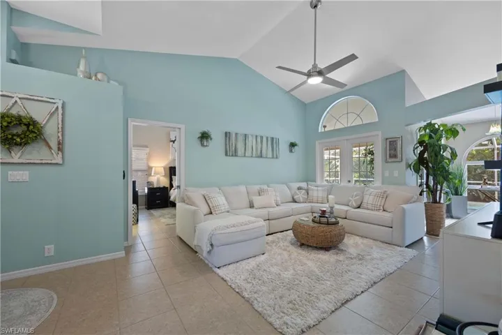 Tiled living room featuring french doors, high vaulted ceiling, and ceiling fan