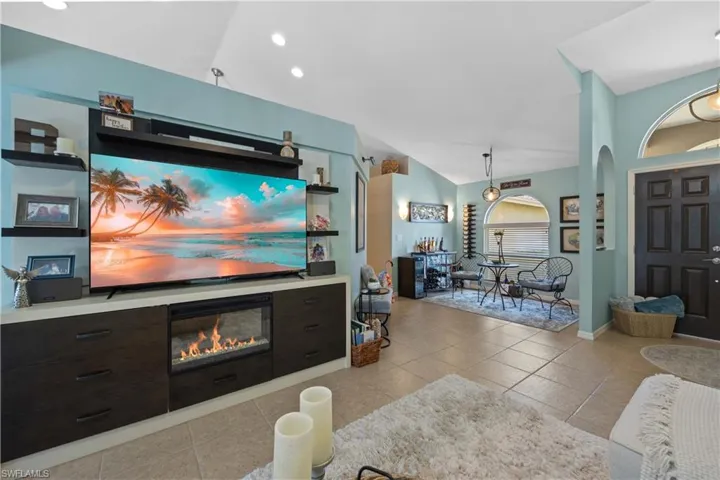Living room with vaulted ceiling and light tile patterned flooring