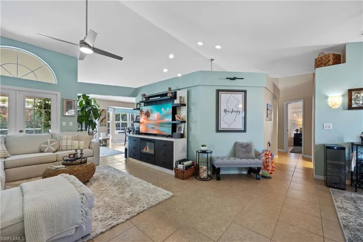 Living room with wine cooler, ceiling fan, french doors, lofted ceiling, and light tile patterned flooring