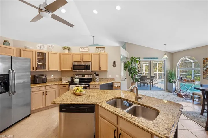 Kitchen with sink, a center island with sink, light brown cabinets, and appliances with stainless steel finishes