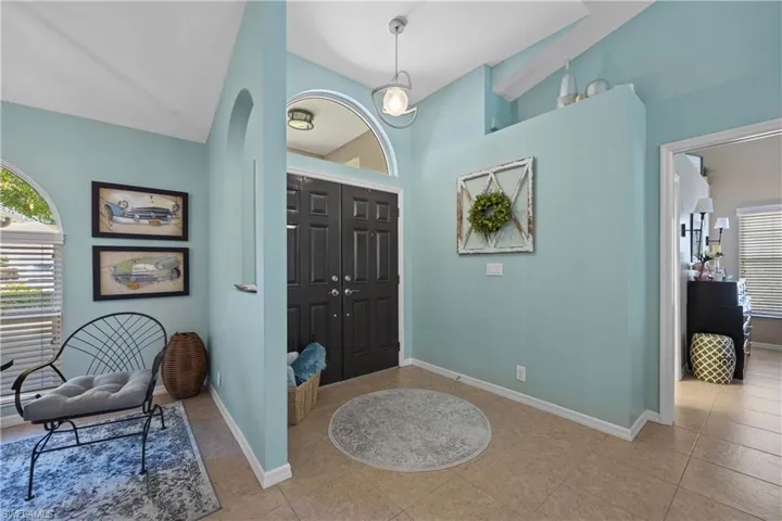 Tiled foyer featuring vaulted ceiling