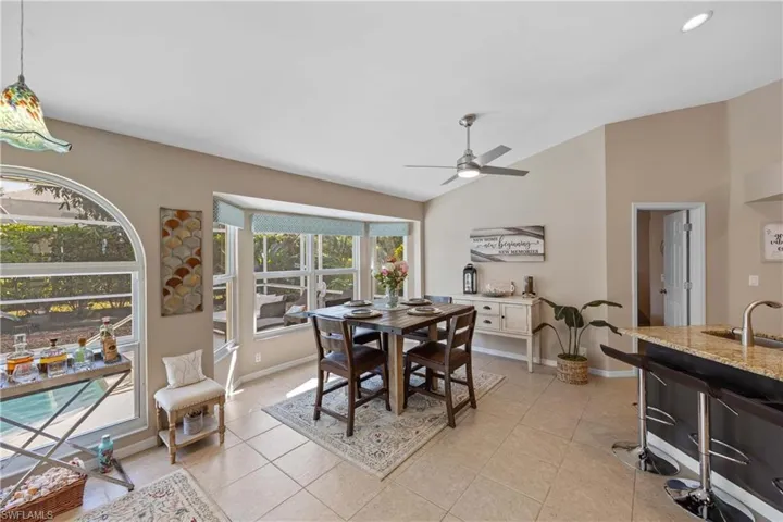 Dining space with vaulted ceiling, ceiling fan, light tile patterned floors, and sink