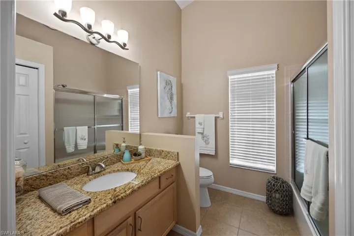 Bathroom featuring toilet, an enclosed shower, vanity, and tile patterned flooring