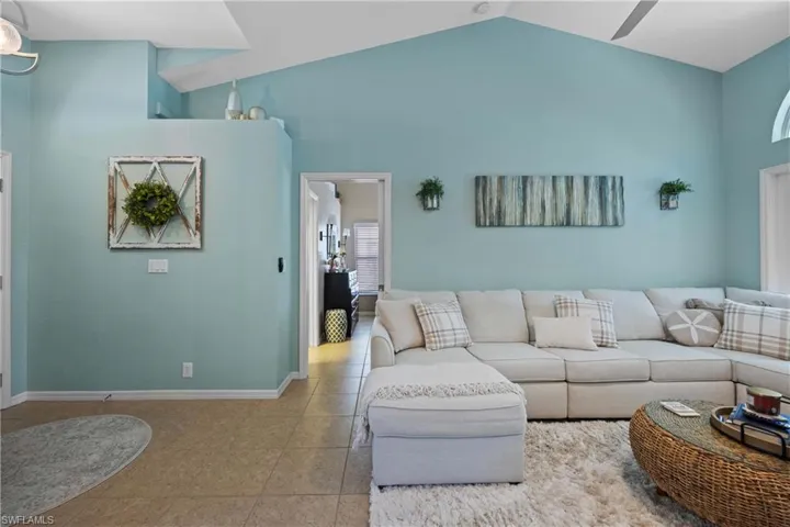 Tiled living room featuring high vaulted ceiling and ceiling fan
