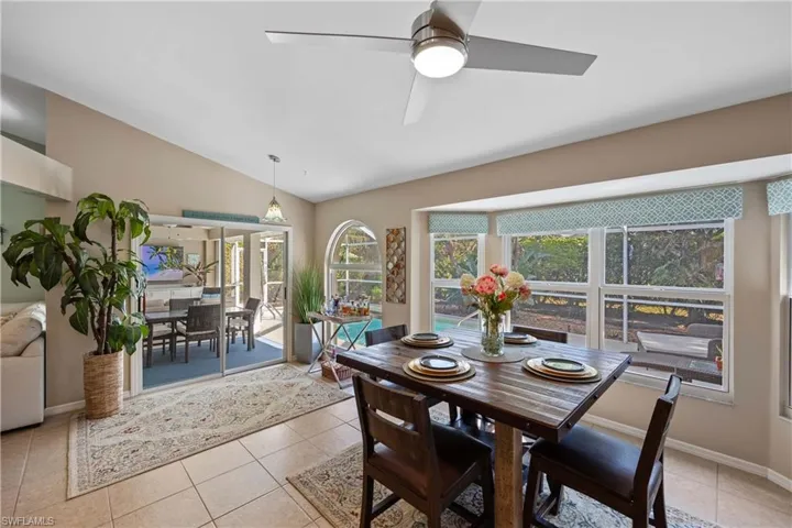 Dining room with ceiling fan, light tile patterned flooring, and lofted ceiling