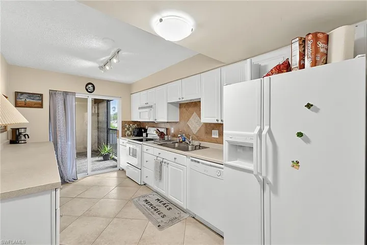 Kitchen featuring white cabinetry, white appliances, neutral countertops, and a tiled backsplash