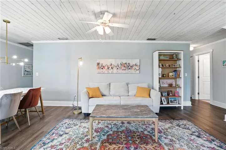 Living area featuring crown molding, an office area, a ceiling fan, dark wood-style flooring, and wooden ceiling