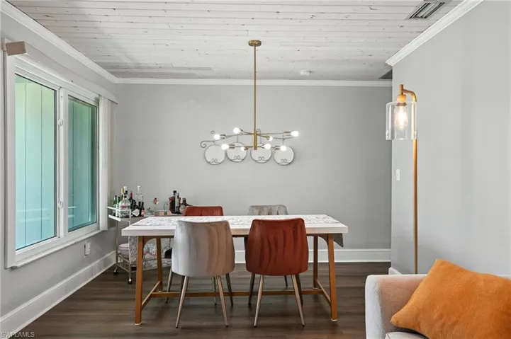 Dining area featuring dark wood-style floors, ornamental molding, and a chandelier