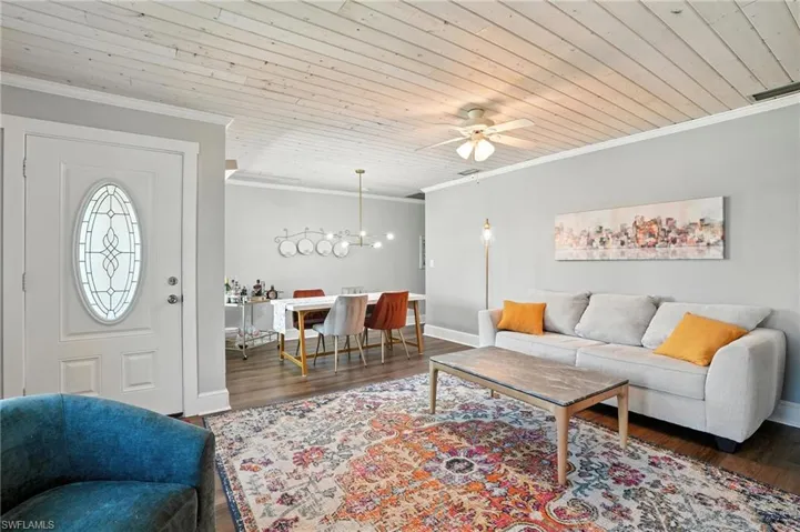 Living area with ornamental molding, wood finished floors, ceiling fan, and wooden ceiling