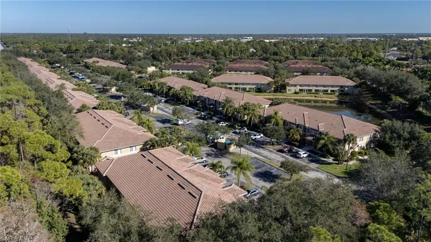 Aerial view of residential area with a nearby body of water and a tree filled landscape