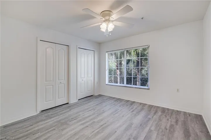 Unfurnished bedroom with multiple closets, light wood-type flooring, and a ceiling fan