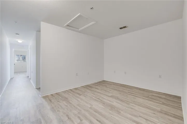 Unfurnished room featuring attic access and light wood-style flooring