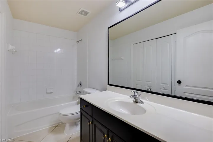 Full bath featuring  shower combination, vanity, light tile patterned floors, and a closet
