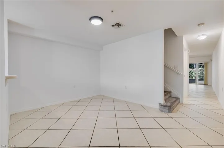 Unfurnished room featuring stairway and light tile patterned floors