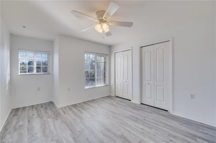 Unfurnished bedroom featuring two closets, light wood-type flooring, and a ceiling fan