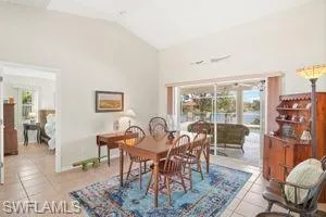 Dining space with tile patterned floors and high vaulted ceiling