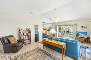 Tiled living room with lofted ceiling and a ceiling fan