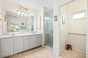 Bathroom featuring a shower stall, baseboards, tile patterned flooring, and double vanity