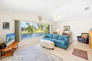 Tiled living room featuring lofted ceiling, visible vents, and ceiling fan