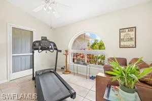Workout area with tile patterned floors, lofted ceiling, and a ceiling fan
