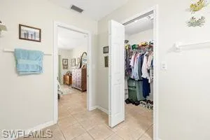 Hall with baseboards, visible vents, and light tile patterned floors