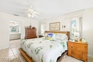Bedroom with light tile patterned floors, baseboards, connected bathroom, visible vents, and a ceiling fan