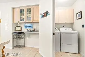 Laundry room featuring light tile patterned flooring, washing machine and dryer, baseboards, and cabinet space