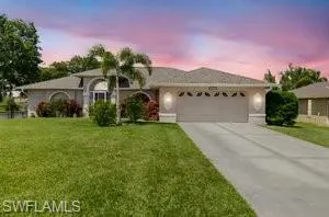 Ranch-style house featuring concrete driveway, a garage, and a lawn