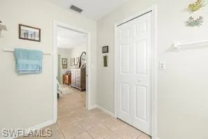 Hall with light tile patterned flooring, baseboards, and visible vents
