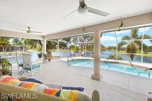 Pool featuring a water view, glass enclosure, and a patio area
