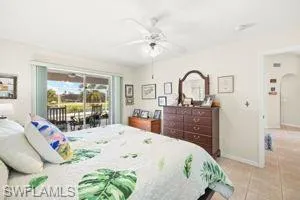 Bedroom with baseboards, access to outside, light tile patterned flooring, arched walkways, and ceiling fan