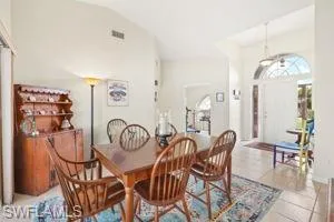 Dining room with tile patterned floors, vaulted ceiling, and visible vents