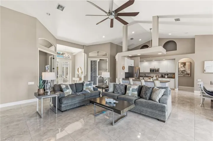Living area with arched walkways, ceiling fan, high vaulted ceiling, french doors, and recessed lighting