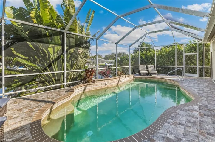 Swimming pool featuring glass enclosure, a sunroom, and a patio area